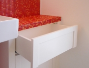 Modernes Badezimmer mit weißen Möbeln und auffälligen roten Mosaikfliesen an Waschtisch und Wänden