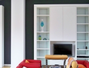Großer, weißer Einbaubücherschrank mit offenen Regalen und unteren Schranktüren, individuell angepasst an die Wohnzimmerwand.